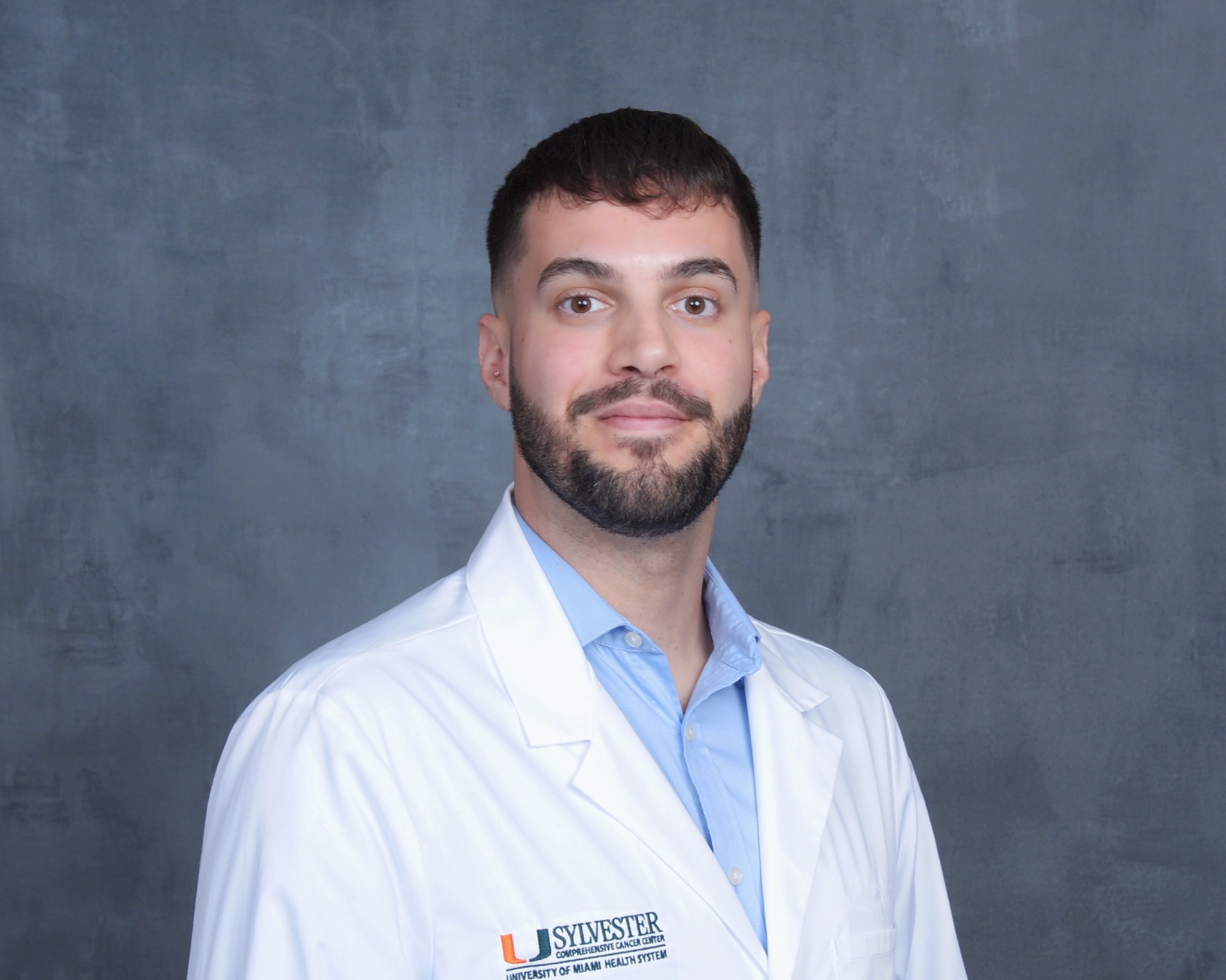 Aaron Riffa wearing a white Sylvester Comprehensive Cancer Center clinical coat